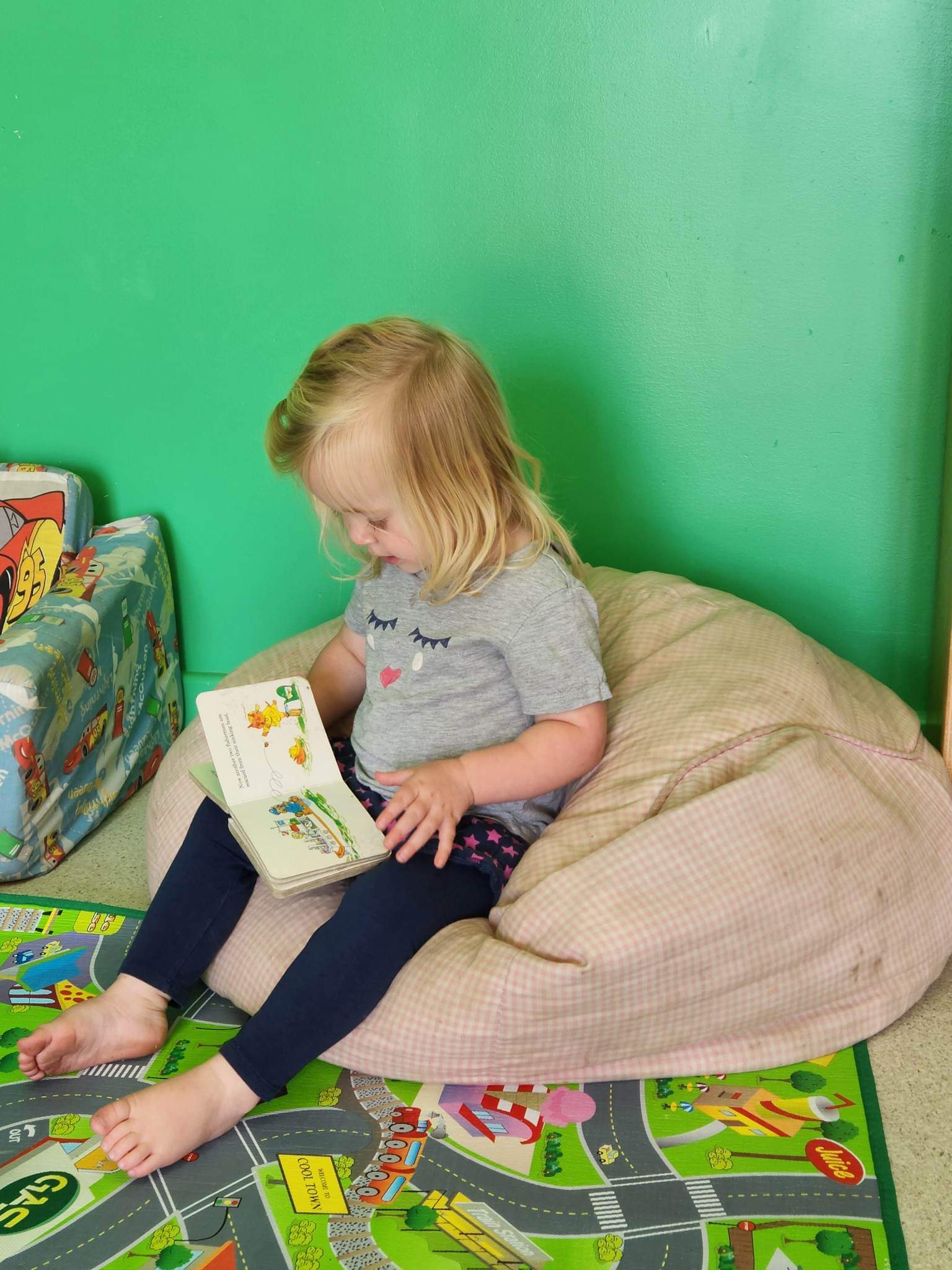 young child sitting in beanbag reading a book