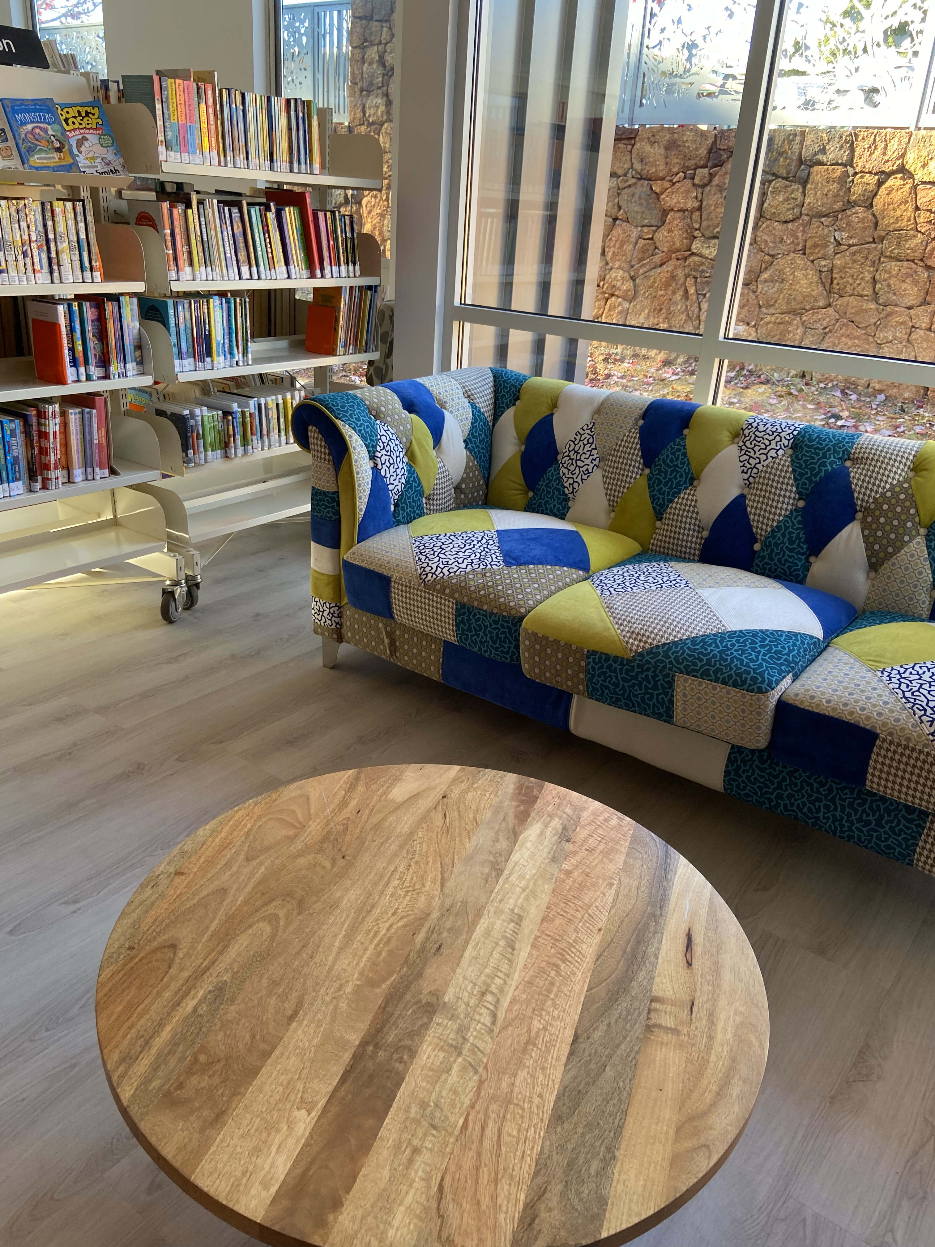 Interior photo of part of new Pemberton Library with bookshelf, couch and coffee table.