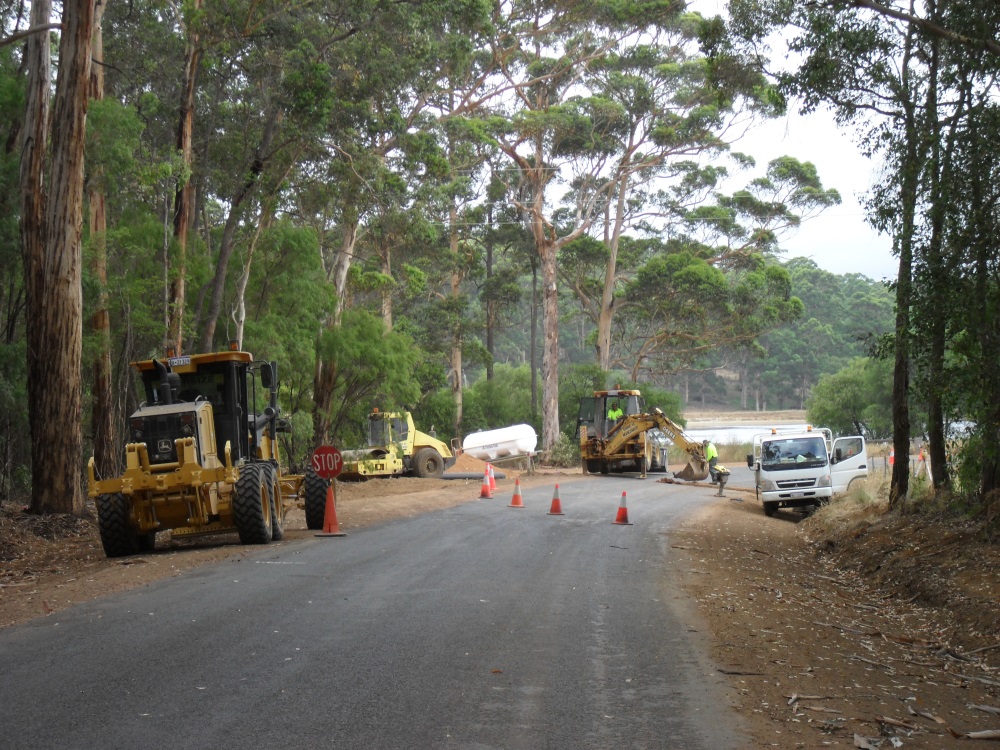 road workers on sealed road with machinery